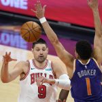 Chicago Bulls center Nikola Vucevic (9) passes the ball as Phoenix Suns guard Devin Booker (1) defends during the second half of an NBA basketball game Wednesday, March 31, 2021, in Phoenix. The Suns won 121-116. (AP Photo/Ross D. Franklin)