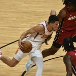Phoenix Suns guard Devin Booker (1) splits the defense of Miami Heat forward Trevor Ariza (0) and forward Precious Achiuwa (5) during the second half of an NBA basketball game Tuesday, March 23, 2021, in Miami. (AP Photo/Jim Rassol)