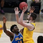 Michigan center Hunter Dickinson shoots over UCLA forward Kenneth Nwuba, left, during the second half of an Elite 8 game in the NCAA men's college basketball tournament at Lucas Oil Stadium, Tuesday, March 30, 2021, in Indianapolis. (AP Photo/Michael Conroy)
