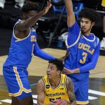 Michigan guard Eli Brooks, center, looks to shoot between UCLA forward Kenneth Nwuba, left, and guard Johnny Juzang (3) during the second half of an Elite 8 game in the NCAA men's college basketball tournament at Lucas Oil Stadium, Tuesday, March 30, 2021, in Indianapolis. (AP Photo/Darron Cummings)