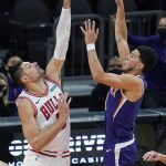Phoenix Suns guard Devin Booker, right, shoots over Chicago Bulls center Nikola Vucevic during the second half of an NBA basketball game Wednesday, March 31, 2021, in Phoenix. (AP Photo/Ross D. Franklin)