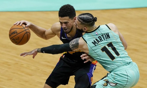 Phoenix Suns guard Devin Booker, left, and Charlotte Hornets forward Cody Martin vie for a loose ba...