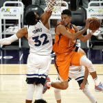 Phoenix Suns guard Devin Booker (1) looks to pass the ball around Minnesota Timberwolves center Karl-Anthony Towns (32) during the second half of an NBA basketball game Friday, March 19, 2021, in Phoenix. Phoenix won 113-101. (AP Photo/Rick Scuteri)