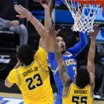 UCLA guard Johnny Juzang (3) shoots over Michigan forward Brandon Johns Jr. (23) and guard Eli Brooks (55) during the second half of an Elite 8 game in the NCAA men's college basketball tournament at Lucas Oil Stadium, Tuesday, March 30, 2021, in Indianapolis. (AP Photo/Darron Cummings)