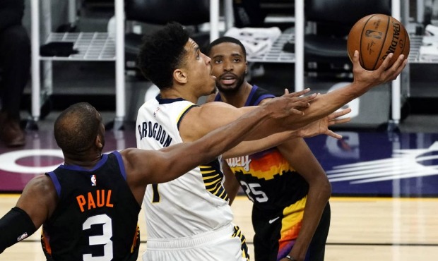 Indiana Pacers guard Malcolm Brogdon (7) drives between Phoenix Suns guard Chris Paul (3) and forwa...