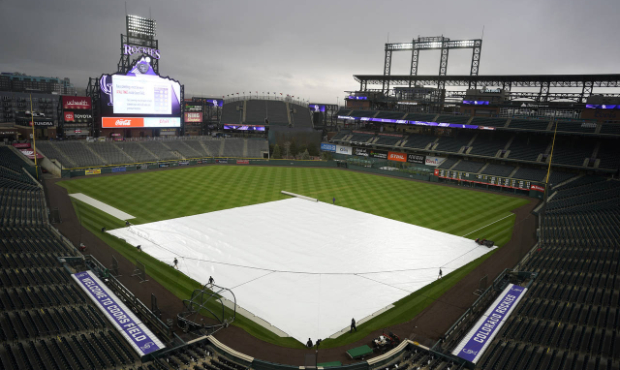 Grounds crew workers pull the tarpaulin as a light rain descends on Coors Field Tuesday, April 6, 2...