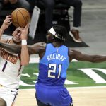 Phoenix Suns' Devin Booker, left, is fouled as he drives to the basket against Milwaukee Bucks' Jrue Holiday, right, during the second half of an NBA basketball game Monday, April 19, 2021, in Milwaukee. (AP Photo/Aaron Gash)