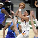 Phoenix Suns' Devin Booker, center, drives to the basket against multiple Milwaukee Bucks defenders during the second half of an NBA basketball game Monday, April 19, 2021, in Milwaukee. (AP Photo/Aaron Gash)