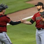 Arizona Diamondbacks' Carson Kelly, left, celebrates with Stefan Crichton, right, after the final out of the ninth inning in the continuation of a baseball game in Cincinnati, Wednesday, April 21, 2021. The game was suspended in the eighth inning the day before due to rain. The Diamondbacks won 5-4. (AP Photo/Aaron Doster)