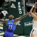 Milwaukee Bucks' P.J. Tucker (17) defends Phoenix Suns' Devin Booker (1) as he shoots during the first half of an NBA basketball game Monday, April 19, 2021, in Milwaukee. (AP Photo/Aaron Gash)