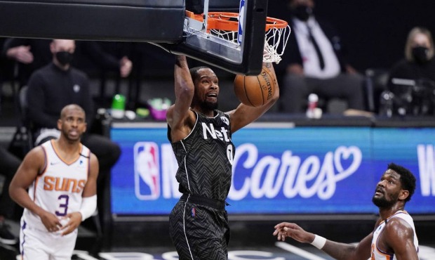 Phoenix Suns guard Chris Paul, left, and Suns center Deandre Ayton, right, watch as Brooklyn Nets f...