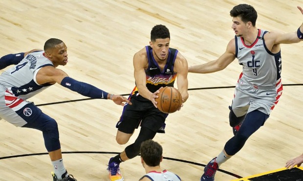 Phoenix Suns guard Devin Booker, center, drives as Washington Wizards forward Deni Avdija (9) and g...
