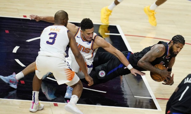Los Angeles Clippers guard Paul George, right, recovers a loose ball in front of Phoenix Suns guard...