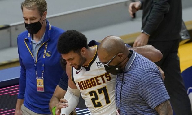 Denver Nuggets guard Jamal Murray (27) is helped off the floor during the second half of an NBA bas...