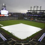 Grounds crew workers pull the tarpulin as a light rain descends on Coors Field Tuesday, April 6, 2021, before the Colorado Rockies host the Arizona Diamondbacks in a baseball game in Denver. Major League Baseball announced that Coors Field will be the venue for the 2021 All Star Game after the Midsummer Classic was moved out of Atlanta because of sweeping changes to voting rights established in the state of Georgia. (AP Photo/David Zalubowski)