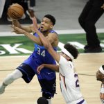Milwaukee Bucks Giannis Antetokounmpo, left, drives to the basket against Phoenix Suns' Cameron Johnson, center, during the first half of an NBA basketball game Monday, April 19, 2021, in Milwaukee. (AP Photo/Aaron Gash)