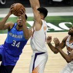 Milwaukee Bucks' Giannis Antetokounmpo, left, drives to the basket against Phoenix Suns' Devin Booker, center, and Mikal Bridges, right, during the first half of an NBA basketball game Monday, April 19, 2021, in Milwaukee. (AP Photo/Aaron Gash)