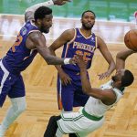 Boston Celtics guard Kemba Walker shoots and scores while falling backward, next to the defense of Phoenix Suns center Deandre Ayton (22) and forward Mikal Bridges (25) in the second half of an NBA basketball game Thursday, April 22, 2021, in Boston. (AP Photo/Elise Amendola)