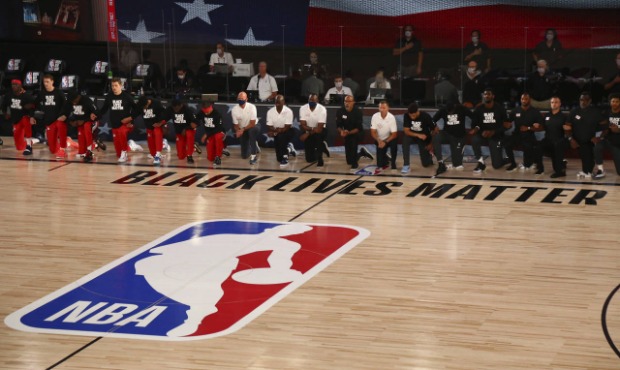 Phoenix Suns and Washington Wizards players kneel behind a Black Lives Matter logo on the court bef...
