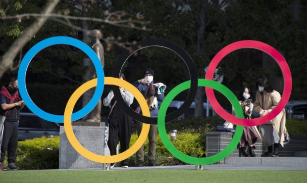 In this March 19, 2021, file photo, people take pictures of the Olympic rings installed by the Japa...