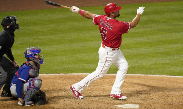 Los Angeles Angels' Albert Pujols, right, hits a solo home run as Texas Rangers catcher Jose Trevin...