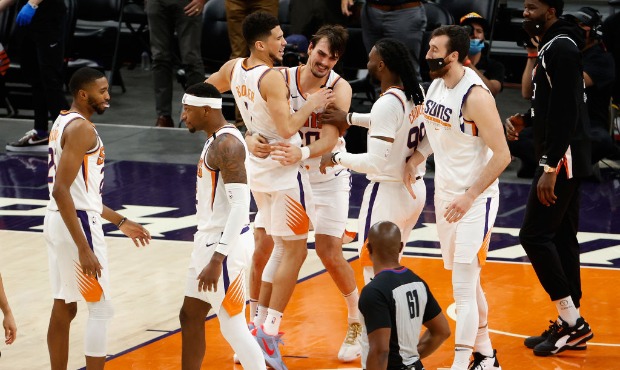 Devin Booker #1 of the Phoenix Suns celebrates with Dario Saric #20, Jae Crowder #99 and Frank Kami...