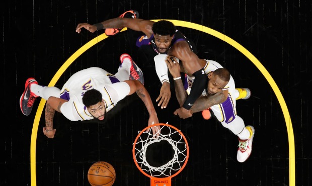 Anthony Davis #3 and LeBron James #23 of the Los Angeles Lakers block out Deandre Ayton #22 of the ...