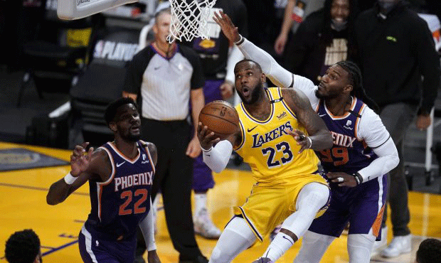 Los Angeles Lakers forward LeBron James, center, scores past Phoenix Suns forward Jae Crowder, righ...