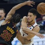 Phoenix Suns' Devin Booker, right, passes against Cleveland Cavaliers' Isaac Okoro in the first half of an NBA basketball game, Tuesday, May 4, 2021, in Cleveland. (AP Photo/Tony Dejak)