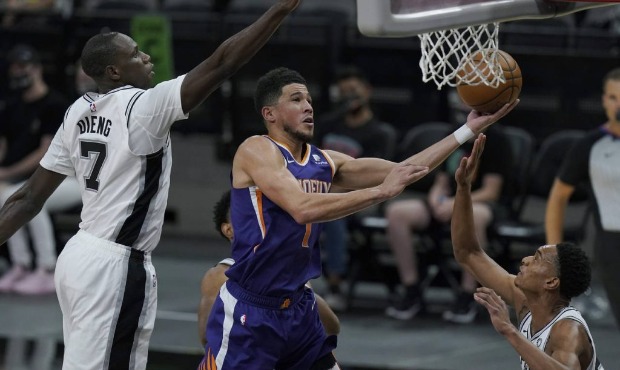 Phoenix Suns guard Devin Booker (1) drives to the basket past San Antonio Spurs center Gorgui Dieng...