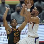 Phoenix Suns' Devin Booker, right, drives to the basket against Cleveland Cavaliers' Isaac Okoro in the first half of an NBA basketball game, Tuesday, May 4, 2021, in Cleveland. (AP Photo/Tony Dejak)