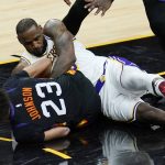 Los Angeles Lakers forward LeBron James, right, battles with Phoenix Suns forward Cameron Johnson, left, for a loose ball during the second half of Game 1 of their NBA basketball first-round playoff series Sunday, May 23, 2021, in Phoenix. The Suns defeated the Lakers 99-90. (AP Photo/Ross D. Franklin)
