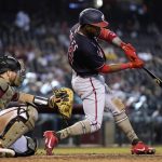 Washington Nationals' Victor Robles, right, connects for a double as Arizona Diamondbacks catcher Stephen Vogt, left, reaches for the ball during the eighth inning of a baseball game Sunday, May 16, 2021, in Phoenix. (AP Photo/Ross D. Franklin)