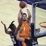 
              Phoenix Suns guard Devin Booker (1) shoots over New York Knicks forward Reggie Bullock (25) and center Taj Gibson during the first half of an NBA basketball game Friday, May 7, 2021, in Phoenix. (AP Photo/Rick Scuteri)
            