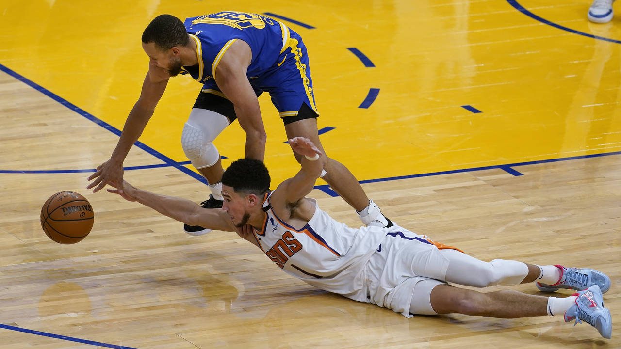 Golden State Warriors guard Stephen Curry, top, reaches for the ball over Phoenix Suns guard Devin ...