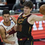 Cleveland Cavaliers' Cedi Osman, right, his fouled by Phoenix Suns' Devin Booker in overtime of an NBA basketball game, Tuesday, May 4, 2021, in Cleveland. Phoenix won 134-118 in overtime. (AP Photo/Tony Dejak)