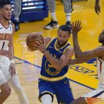 Golden State Warriors guard Stephen Curry, middle, drives between Phoenix Suns guard Devin Booker (1) and forward Mikal Bridges during the first half of an NBA basketball game in San Francisco, Tuesday, May 11, 2021. (AP Photo/Jeff Chiu)