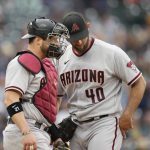 Arizona Diamondbacks catcher Stephen Vogt, left, confers with starting pitcher Madison Bumgarner after Bumgarner gave up a single to Colorado Rockies Brendan Rodgers which brought in two runs in the fourth inning of a baseball game Saturday, May 22, 2021, in Denver. (AP Photo/David Zalubowski)