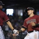 Arizona Diamondbacks' Daulton Varsho, right, celebrates his run scored against the Colorado Rockies with teammate Merrill Kelly, left, during the second inning of a baseball game Sunday, May 2, 2021, in Phoenix. (AP Photo/Ross D. Franklin)
