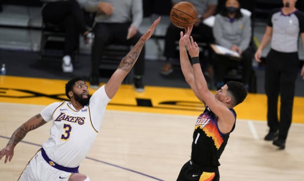 Phoenix Suns guard Devin Booker, right, shoots over Los Angeles Lakers forward Anthony Davis (3) du...