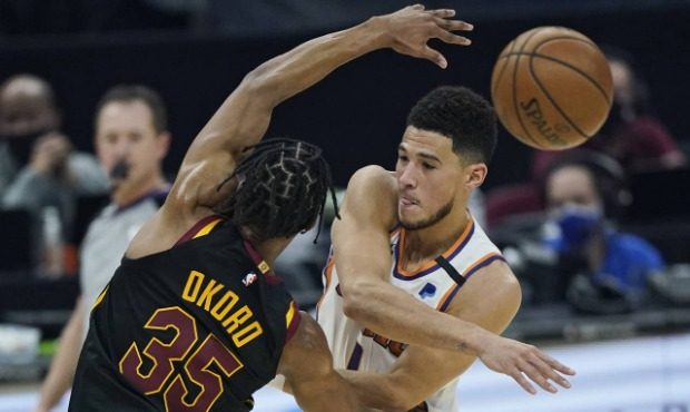 Phoenix Suns' Devin Booker, right, passes against Cleveland Cavaliers' Isaac Okoro in the first hal...