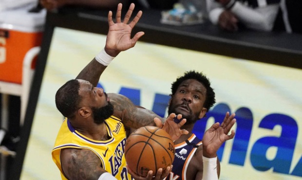 Los Angeles Lakers forward LeBron James, left, shoots as Phoenix Suns center Deandre Ayton defends ...