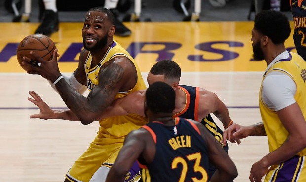 LeBron James #23 of the Los Angeles Lakers controls the ball as Draymond Green #23 and Stephen Curr...