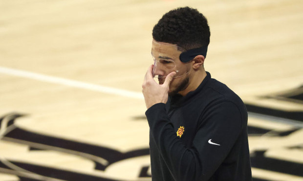 Devin Booker #1 of the Phoenix Suns adjusts his face guard during warm-ups before the start of game...
