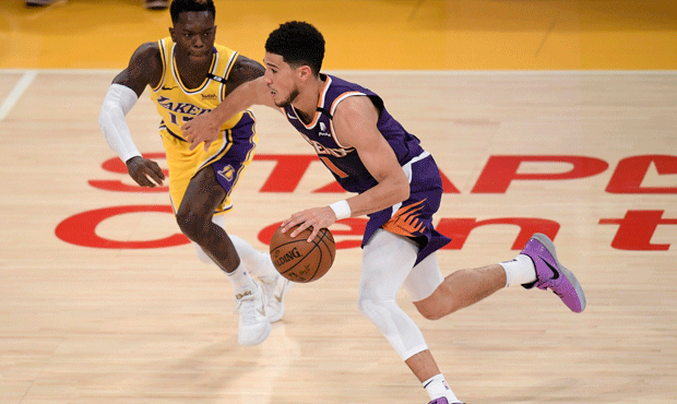 Devin Booker of the Phoenix Suns dribbles in front of Dennis Schroder of the Los Angeles Lakers in ...