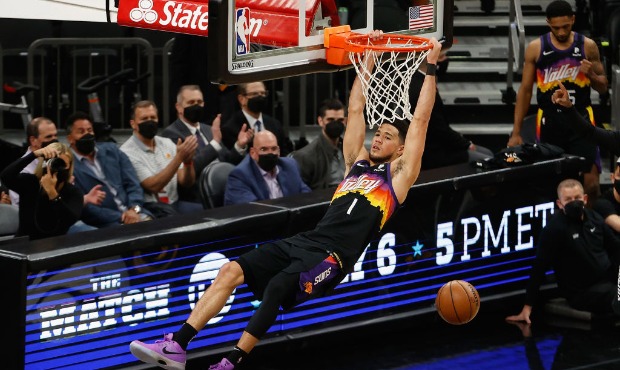 Devin Booker #1 of the Phoenix Suns slam dunks the ball against the Denver Nuggets during the first...