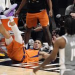 Phoenix Suns guard Devin Booker, left, falls after scoring and drawing a foul as Los Angeles Clippers guard Terance Mann watches during the second half in Game 4 of the NBA basketball Western Conference Finals Saturday, June 26, 2021, in Los Angeles. (AP Photo/Mark J. Terrill)