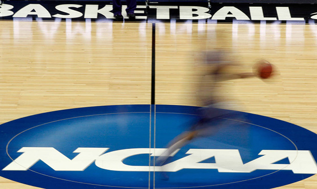 FILE - In this March 14, 2012, file photo, a player runs across the NCAA logo during practice in Pi...