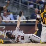 Arizona Diamondbacks' Josh Reddick, left, slides safely into home, scoring off an RBI-double by Eduardo Escobar, as San Diego Padres catcher Webster Rivas looks on during the first inning of a baseball game Saturday, June 26, 2021, in San Diego. (AP Photo/Gregory Bull)