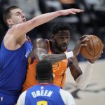 Denver Nuggets center Nikola Jokic, left, and forward JaMychal Green, front, defend against Phoenix Suns center Deandre Ayton during the first half of Game 3 of an NBA second-round playoff series Friday, June 11, 2021, in Denver. (AP Photo/David Zalubowski)